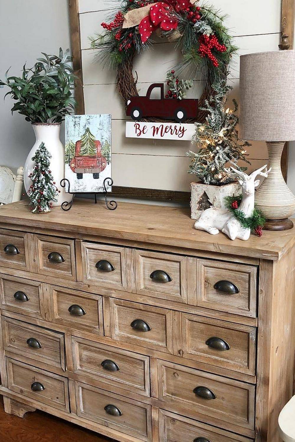 Wreath above the console table along with small illuminated Christmas trees bring festive joy to this entry