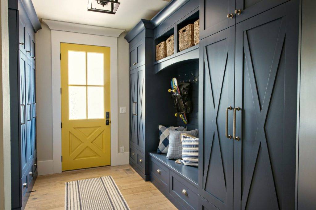 Uma entrada com armários azuis e uma porta frontal amarela.