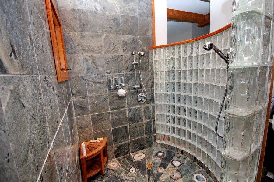 Corner shower with gray floor tiles and a curved glass block wall