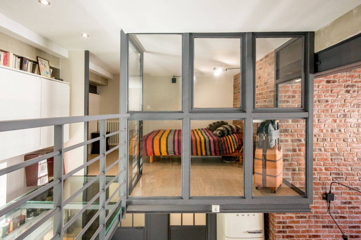 Eclectic loft style bedroom of Paris home with glass walls and cantilevered design