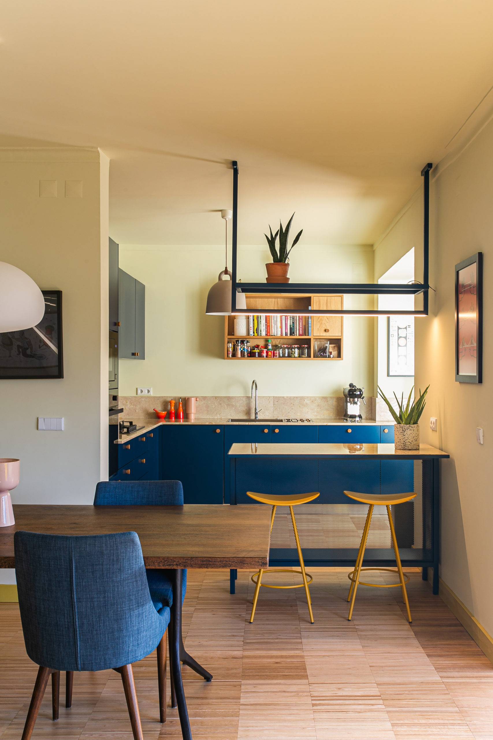 Kitchen and dining area of the apartment with ocean blue cabinets and yellow bar stools