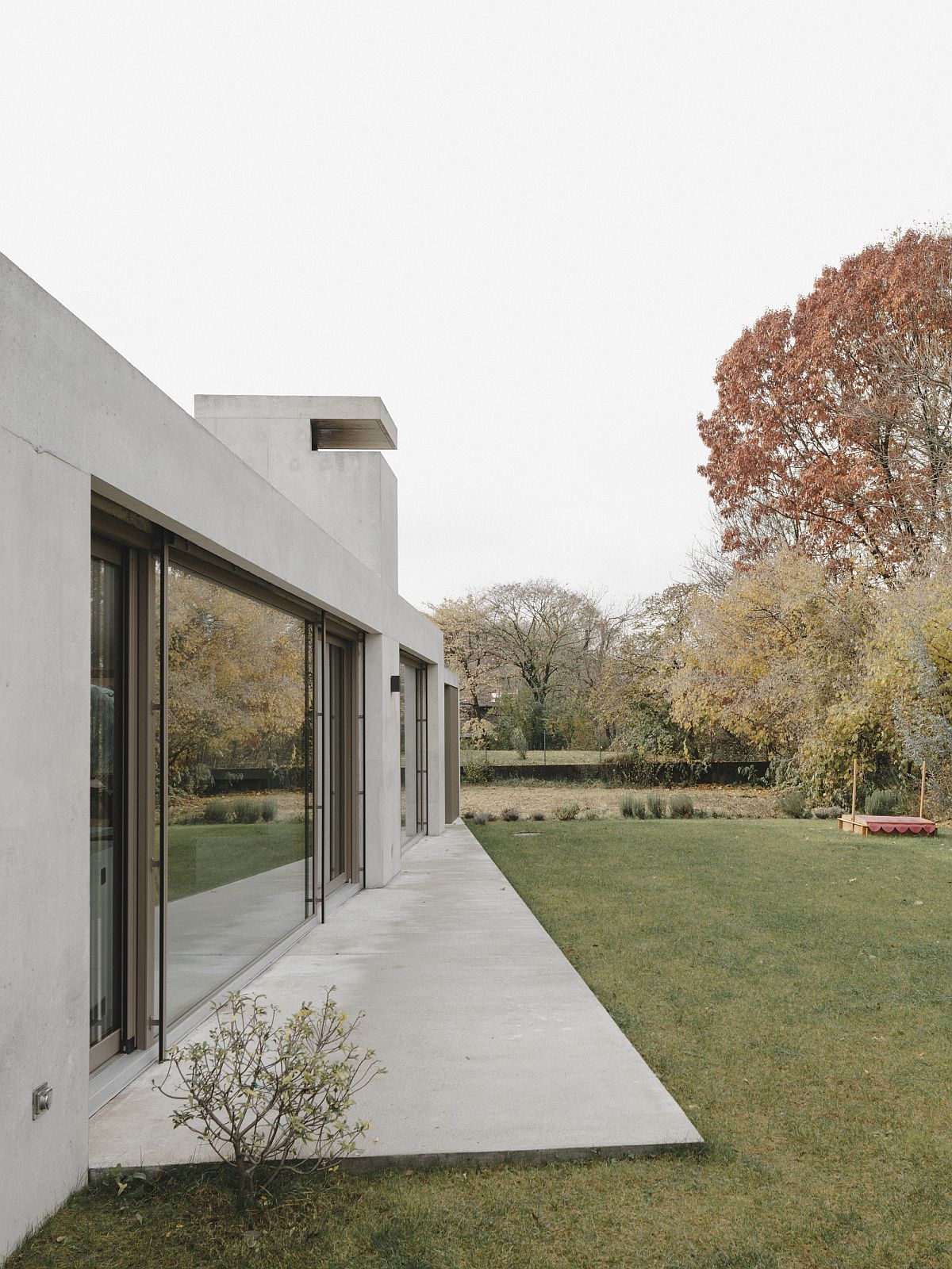 Minimal concrete deck of the house extends into the large backyard