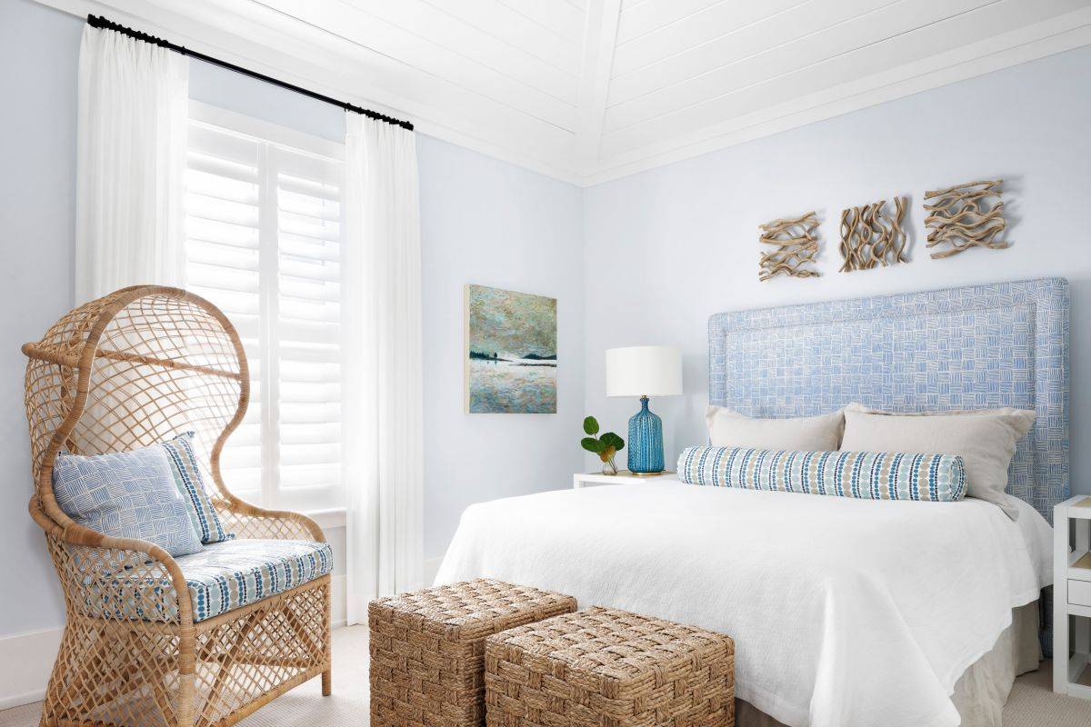 Rattan decor pices accentuate the beachy vibe in this white and light blue bedroom