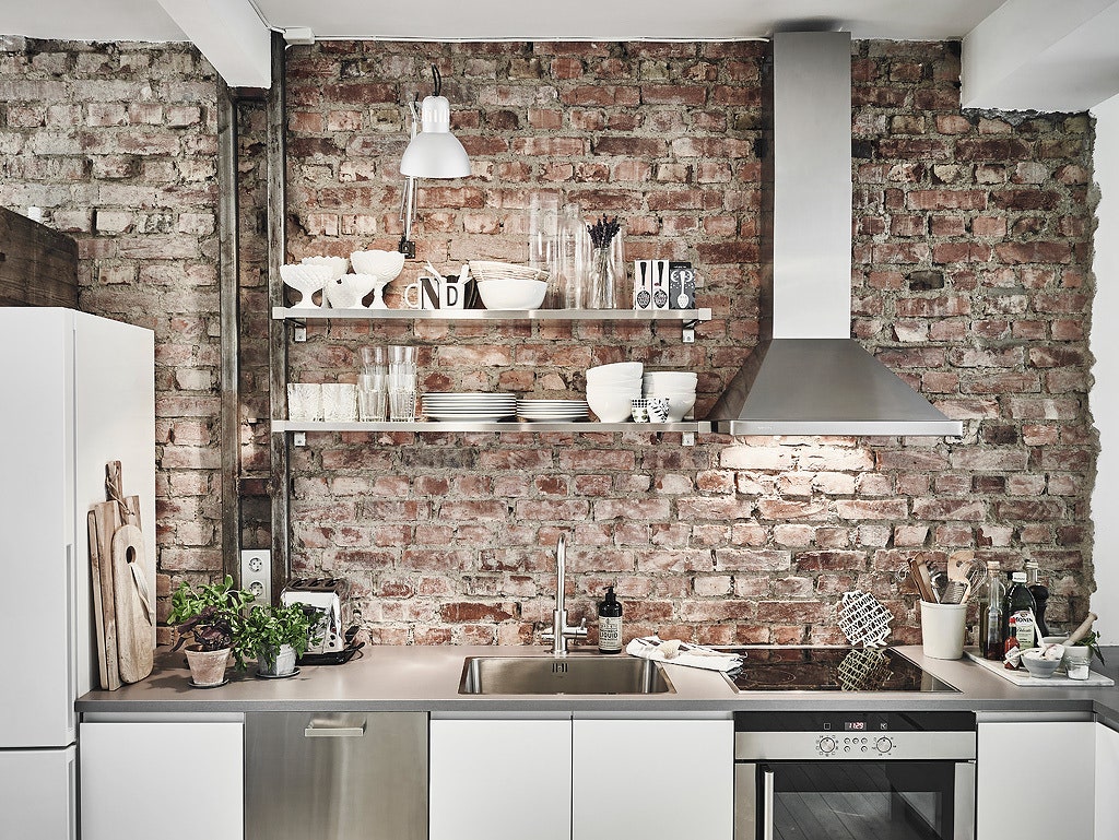 Exposed brick backsplash for rustic appeal (from Architectural Digest)