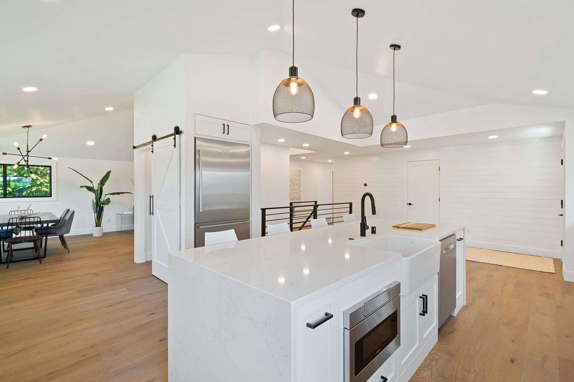 Modern white kitchen with black pendant lights (from Unsplash)