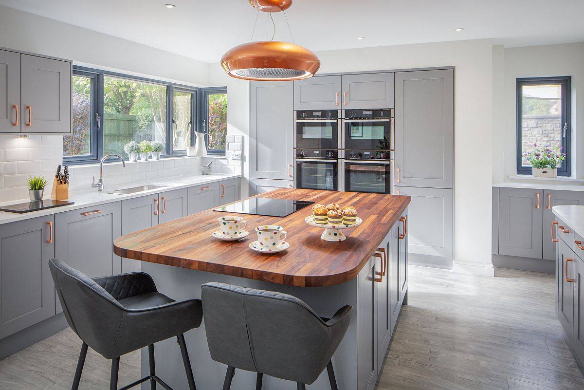 Contemporary kitchen in gray with a fabulous island top in wood along with copper handles and pendant lighting