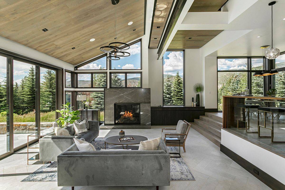 Delightful glass walls and widnows bring the beautiful outdoors inside in this rustic living space