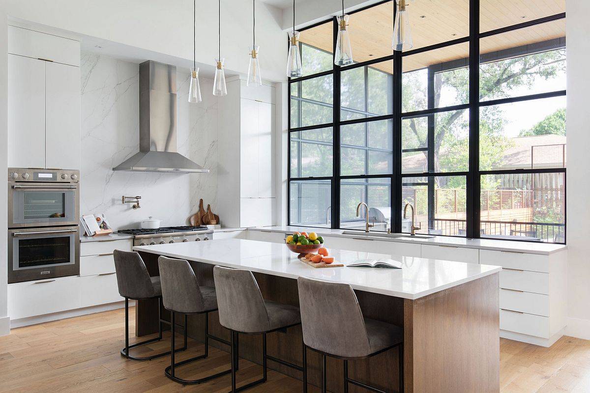 Large, double-height kitchen in white with wood flooring and large window above the counter