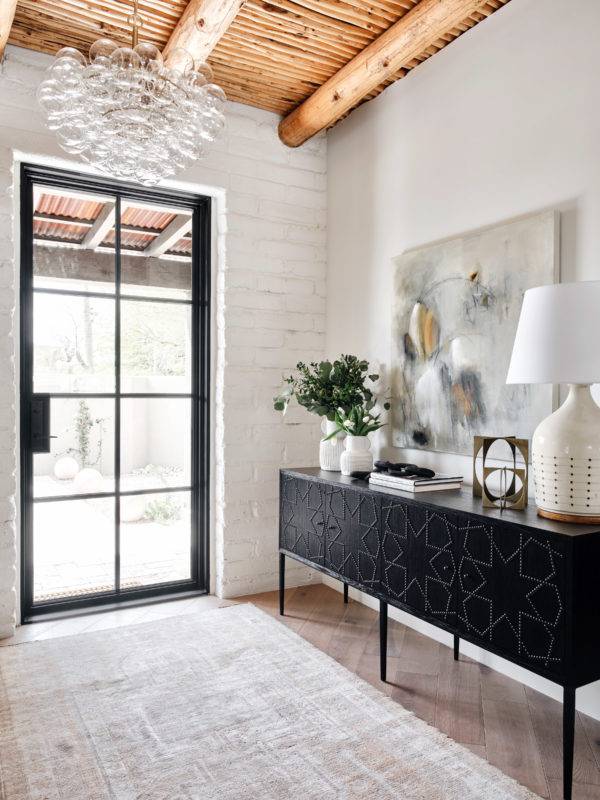 entryway to home with black patterned cabinet and plants