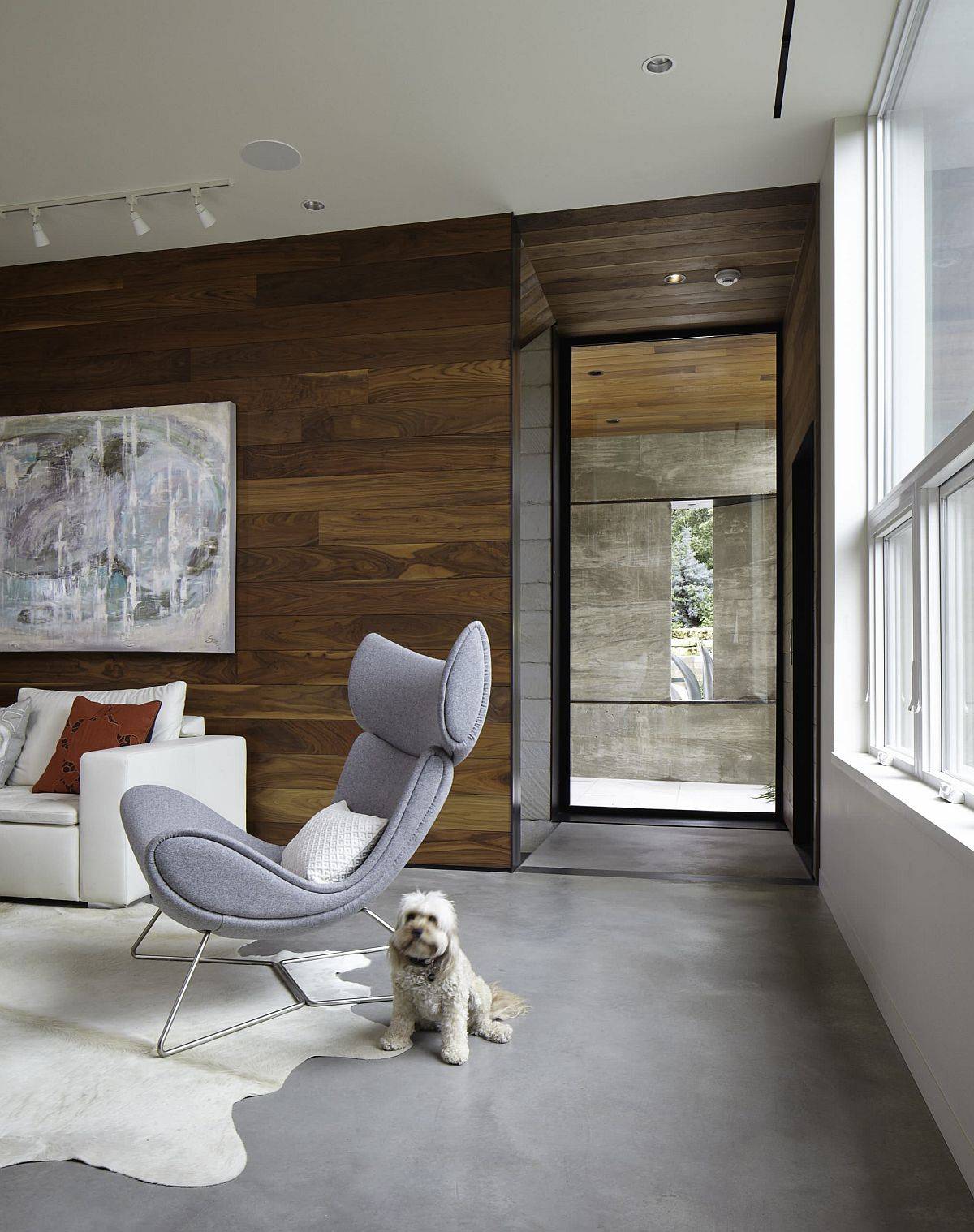 Woodsy walls coupled with stoic concrete flooring in the cozy modern living room