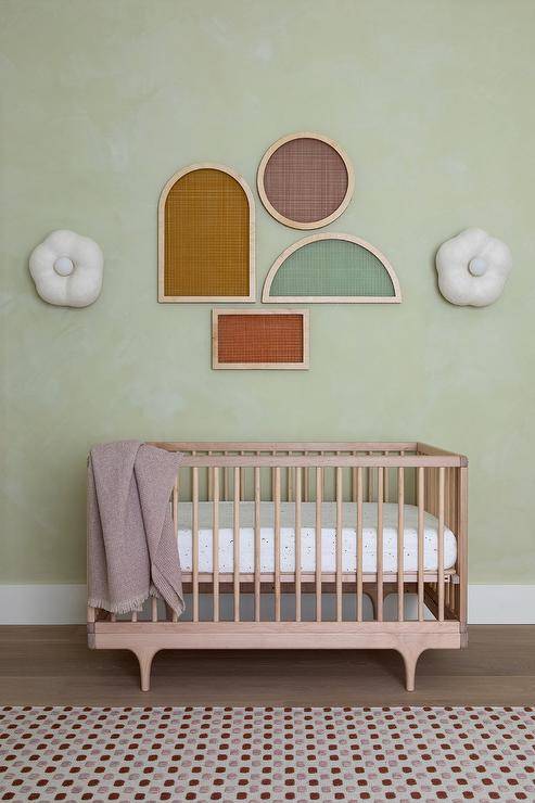 green wall nursery with crib and geometric modern wall art shapes purple blanket