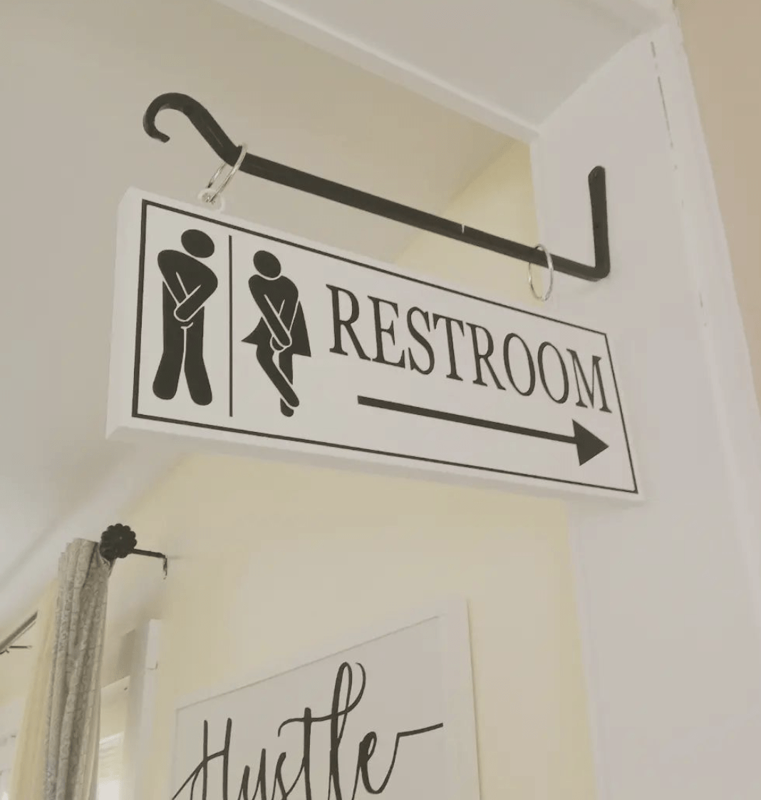 Restroom direction sign hanging on black iron hook