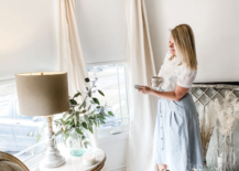 woman standing looking at blinds remote in hand