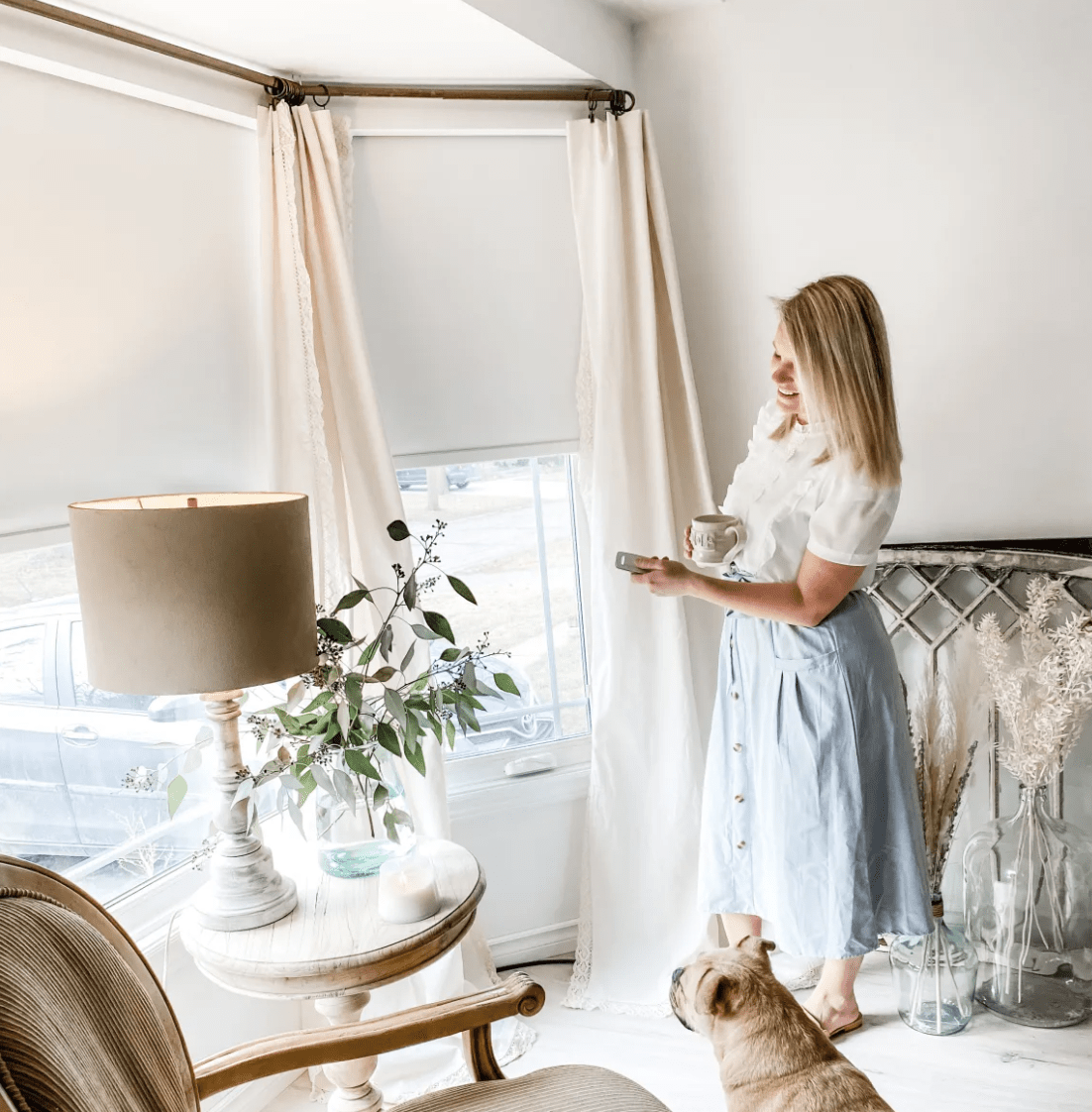 woman standing looking at blinds remote in hand