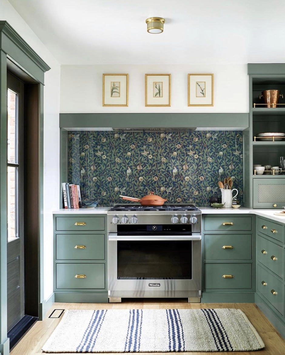 green cabinets gold drawer pulls knobs art photos light wallpaper backsplash orange pot stove stainless steel