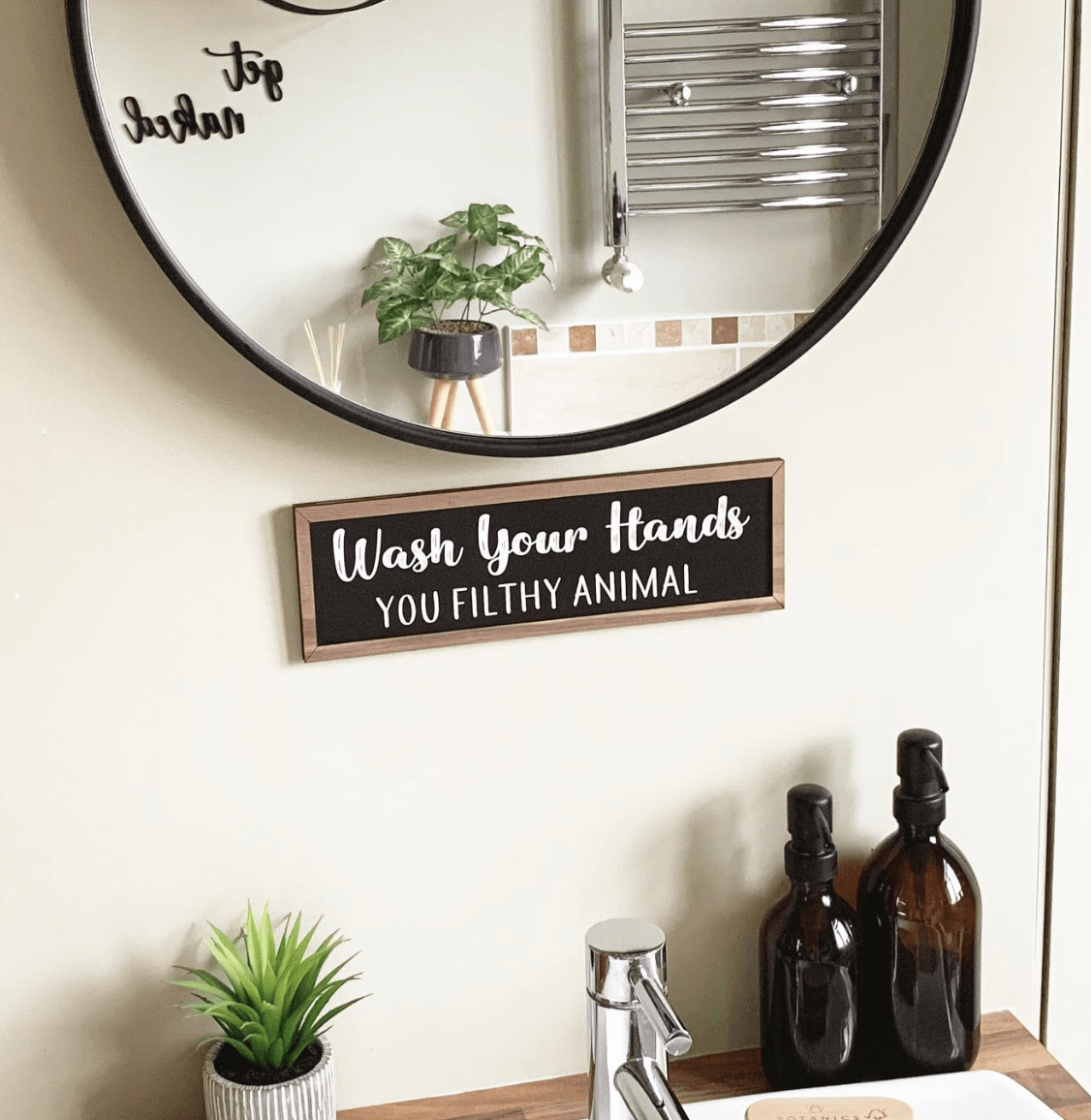 round black mirror bathroom sign amber bottle soap dispensers greenery