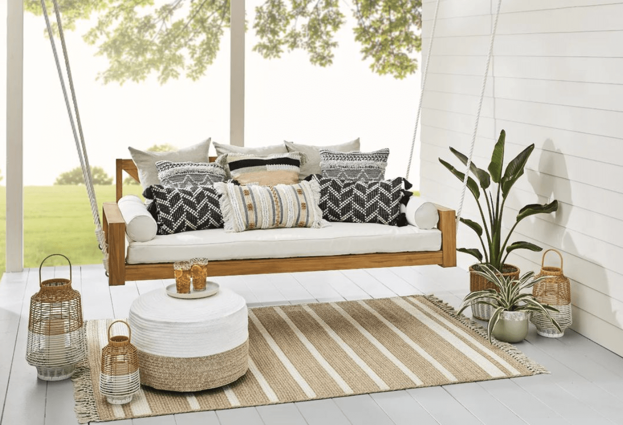 white cushion hanging porch swing wood frame outdoor rug outside lanterns patio
