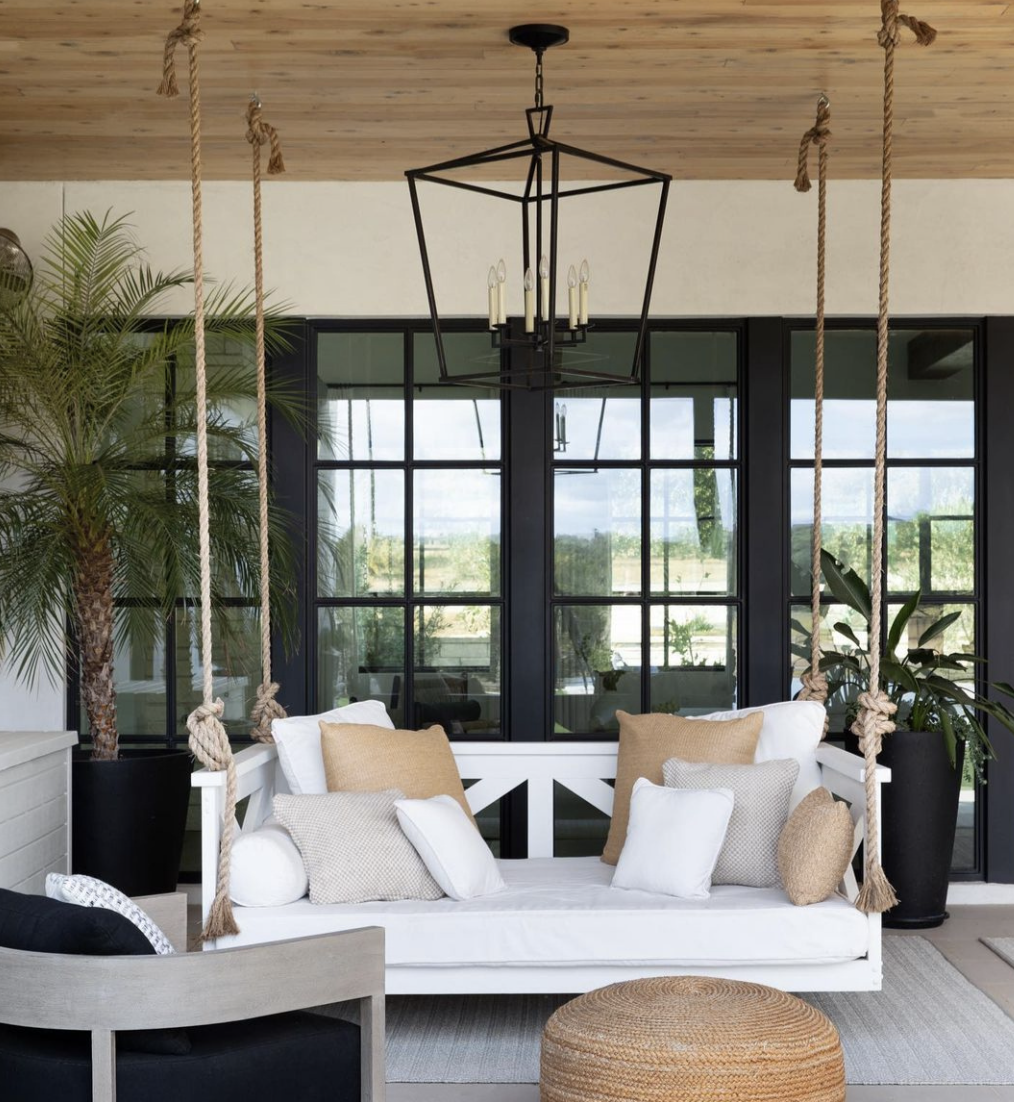 black hanging chandelier middle porch patio hanging bench swing white cushions frame windows wood ceiling