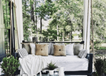 black frame wood porch swing hanging white cushion lantern patio decor