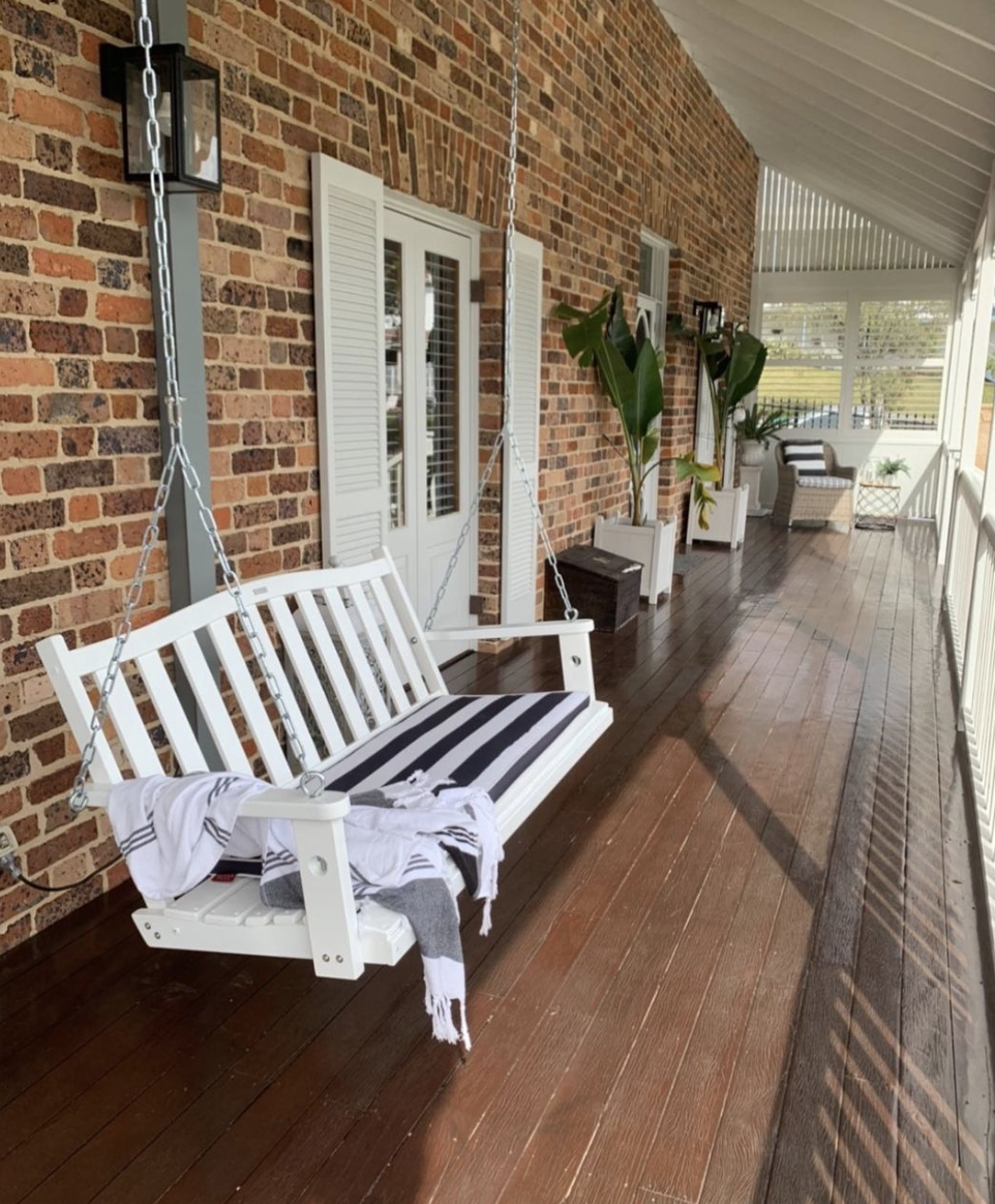 hanging white porch swing brick porch white shutters wood plank floor outside