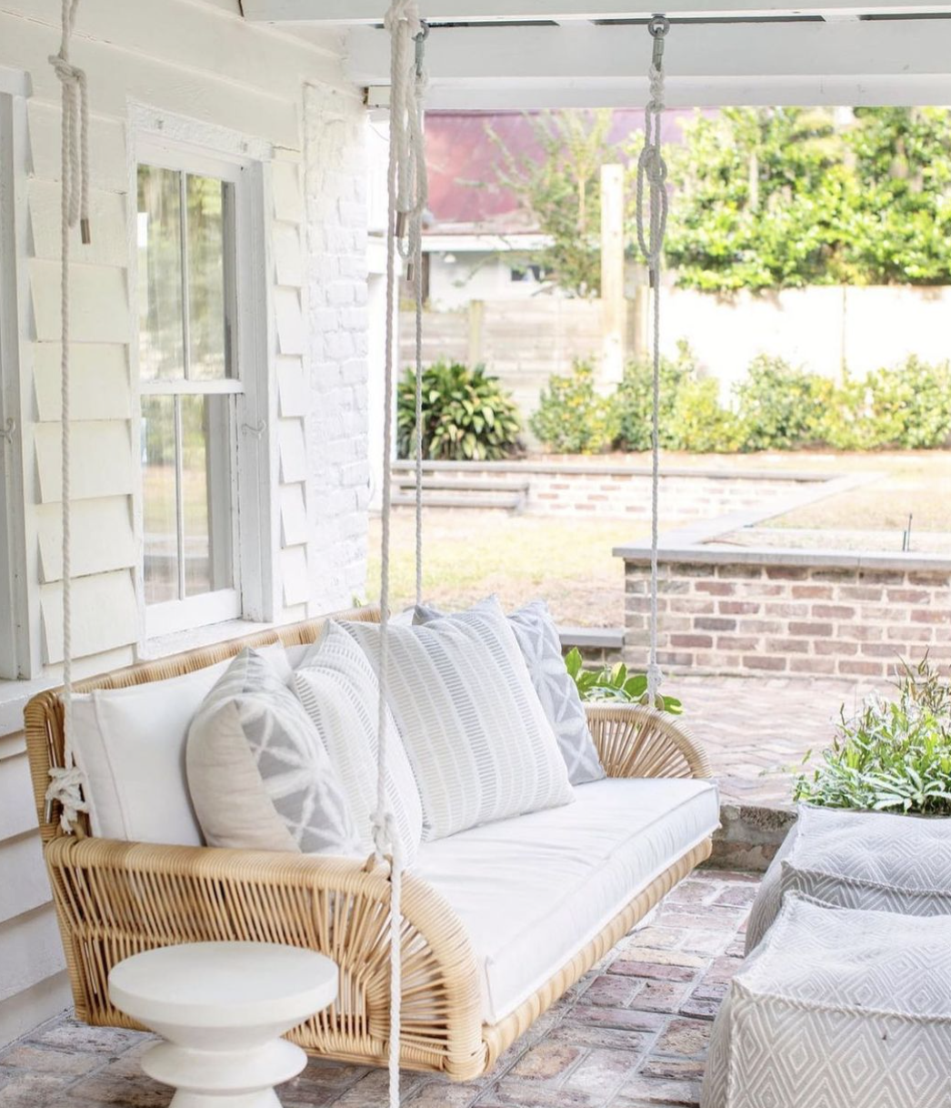 natural wicker patio porch swing white cushions pillows white brick