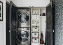 black shutter door closet laundry room white shelving stacked black stainless steel washer and dryer