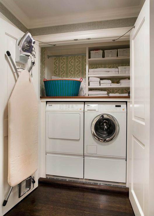 open doors closet laundry room white washer and dryer hanging ironing board shelves baskets