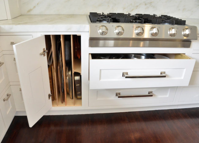 dividers inside cupboard pans cutting boards white cabinetry stove