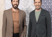 drew and jonathan scott property brothers standing in front of wallpaper wearing suits