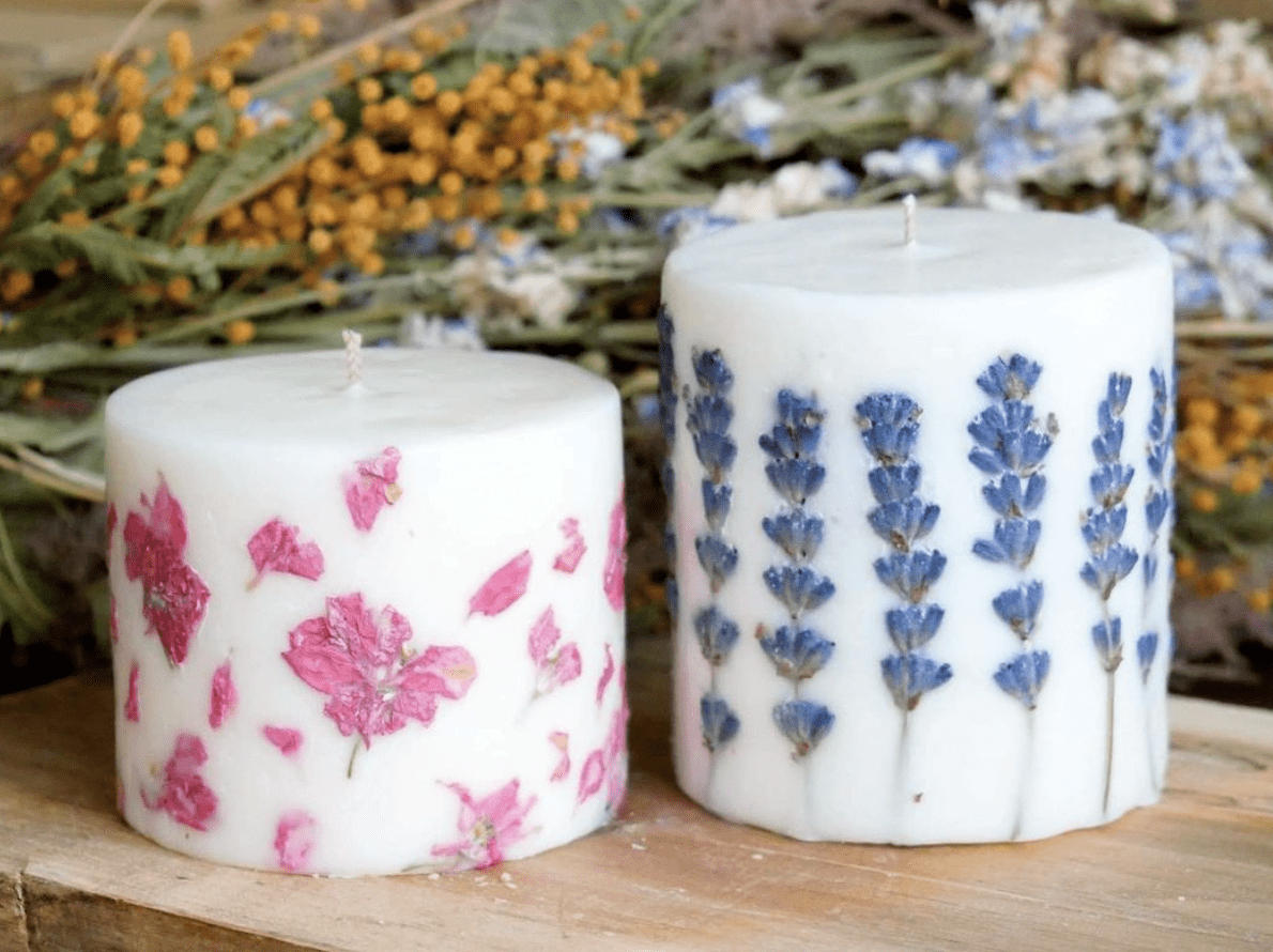 blue and pink flowers embedded into white pillar candles close up