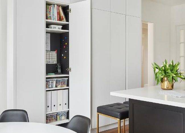 white cabinetry with one door open revealing a hidden command center black leather counter stool chairs table