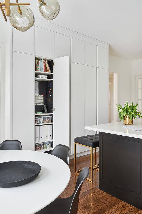 white cabinetry with one door open revealing a hidden command center black leather counter stool chairs table