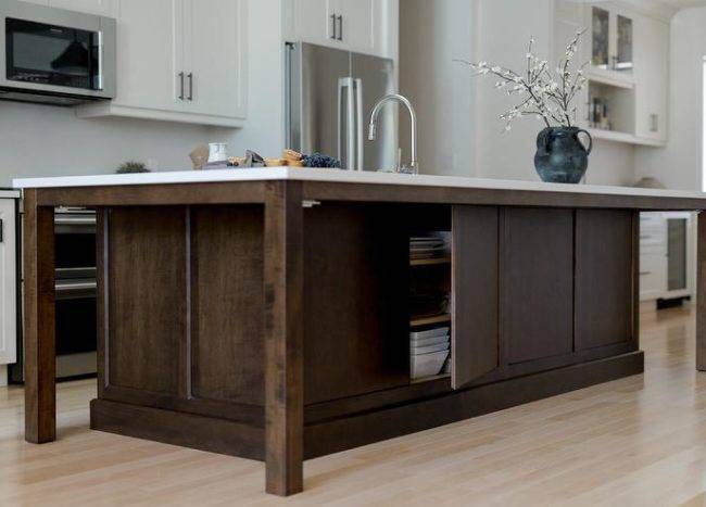 open cupboard door on back of dark wood walnut island kitchen sink white cabinetry