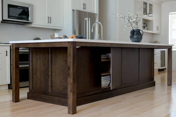 open cupboard door on back of dark wood walnut island kitchen sink white cabinetry