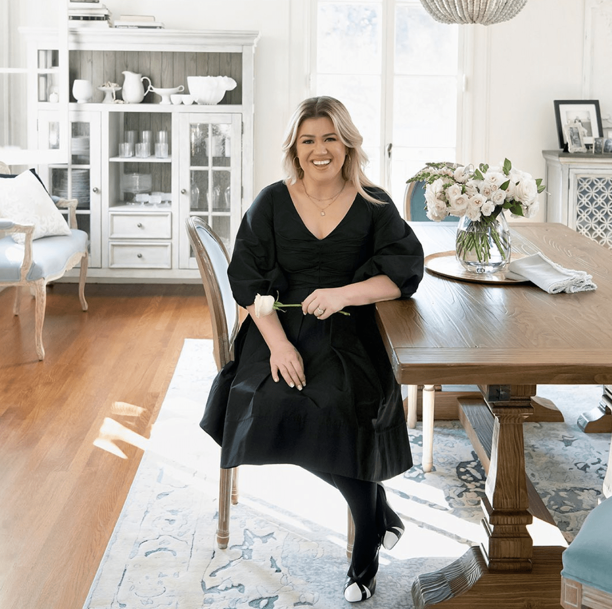 kelly clarkson sitting at a table in a large decorated room