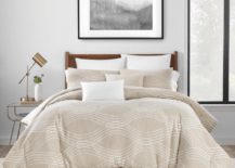 bedding master bed with tan bed covering white pillows in room with lamp on nightstand