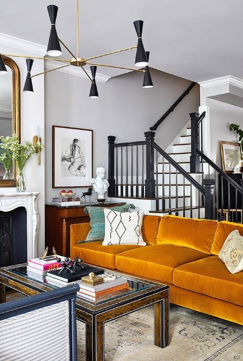 burnt orange sofa in front of black staircase wall art modern lighting