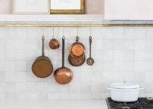 gold rod with hanging copper pans white tile kitchen backsplash modern art cabinetry stove