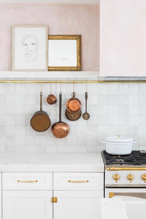gold rod with hanging copper pans white tile kitchen backsplash modern art cabinetry stove