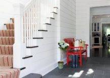 red bench in white hallway with staircase grey flooring runner down stairs