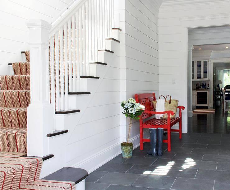 red bench in white hallway with staircase grey flooring runner down stairs