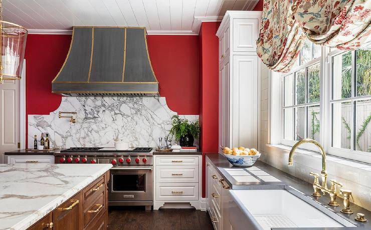 red and white kitchen with gray oven hood large stainless steel stove brown island