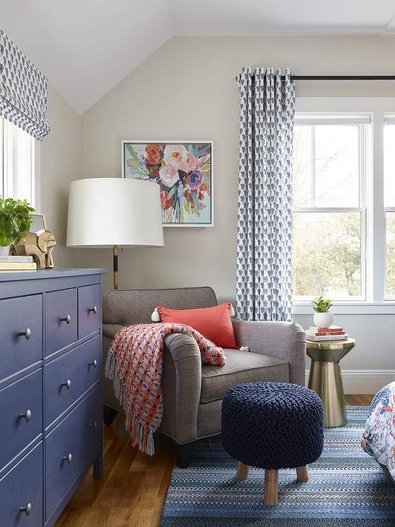 red and blue bedroom with sitting chair throw ottoman lamp with white shade dresser large window with curtains