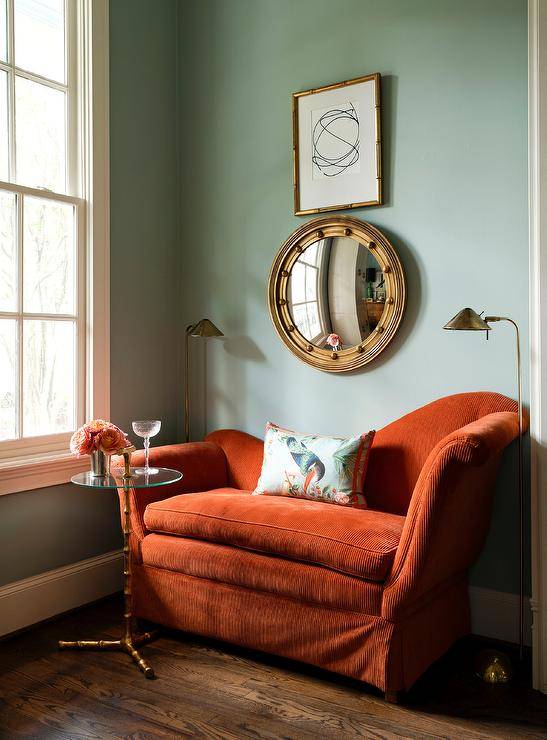 burnt red couch green wall with window mirror and wall art pillow