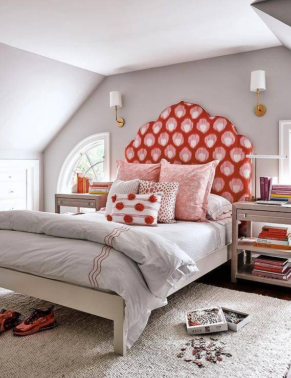 gray walls bedroom with large bed red headboard pillows and gold sconces on wall