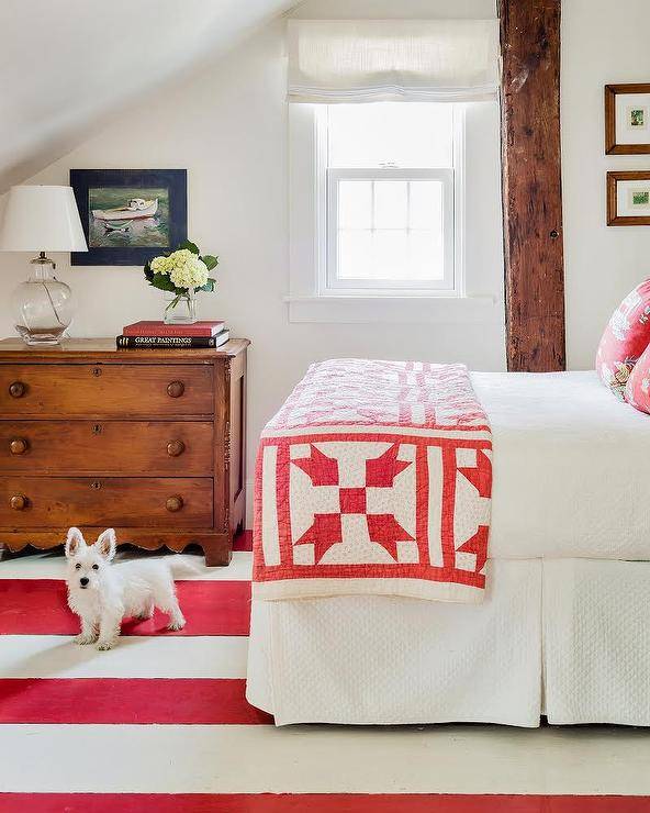 red and white striped carpet in bedroom with bedding throw brown wood dresser and small window beam