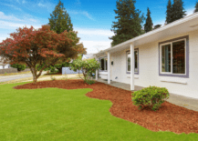 white front house simple landscape grass and red mulch shrubs trees