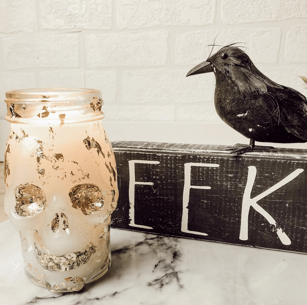 glass skull candle eek black sign with crow sitting on top