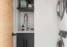 geometric floor tiles stacked white washer and dryer slender small sink black cabinetry white towels countertop pull down faucet laundry room