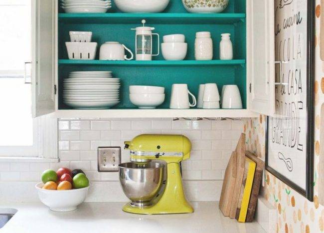 open cupboard kitchen with green background baskets up high on top yellow stand mixer on counter white dishes